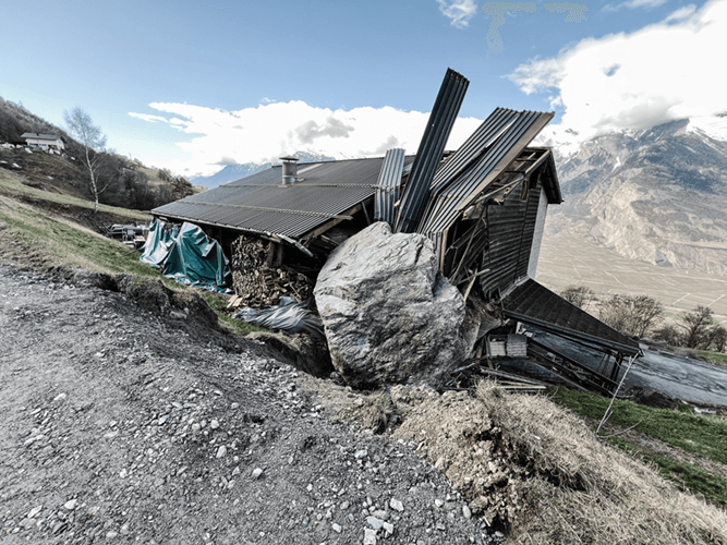 Un grand rocher s'étant écrasé sur un chalet et ayant endommagé le toit et un pan de mur.