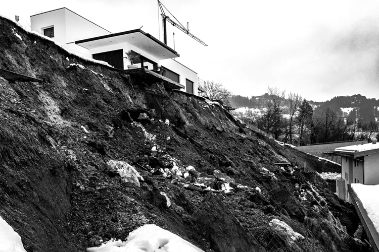 Une photo noir et blanc montrant un glissement de terrain sous une villa en construction.
