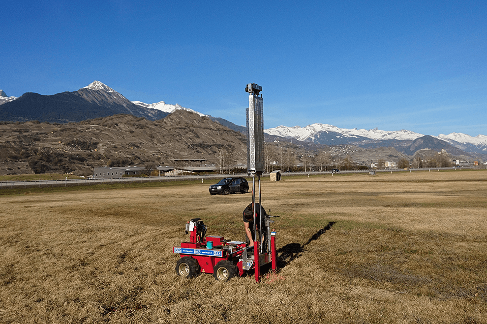 Un ingénieur du Bureau BEG se penche sur une machine de mesure rouge de BEG installée dans la plaine du Rhône.